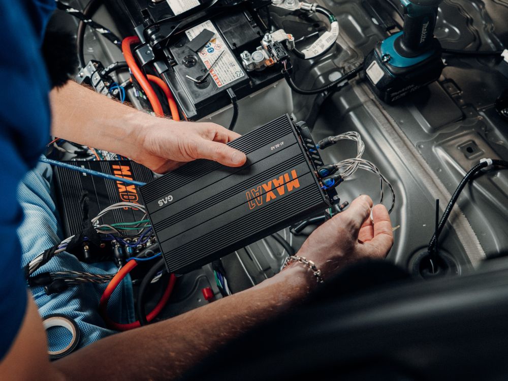 MAX A1-90.4D i en billjudsinstallation i ett par händer, RCA-kablar inkopplade